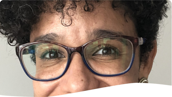 Black woman wearing glasses with very short curly hair and smiling