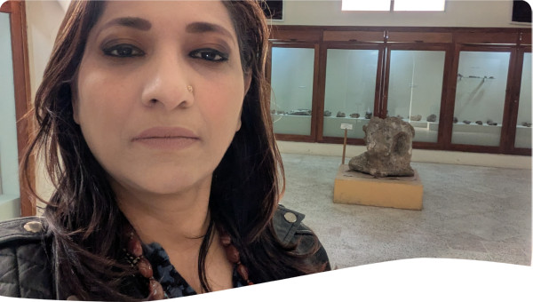 Erum Khan standing inside a museum with cultural displays in the background.