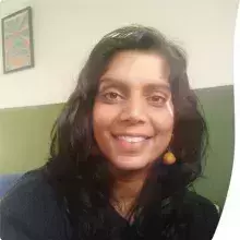 Female, indian origin, wearing blue jumper, yellow earrings, hair down