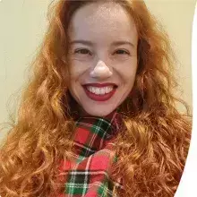 I am a white woman, with long curly red hair, small brown eyes, a wide smile, some wrinkles, a large forehead, an angular face, 1 meter and 65 centimeters tall, wearing a red and green plaid scarf with white stripes.
